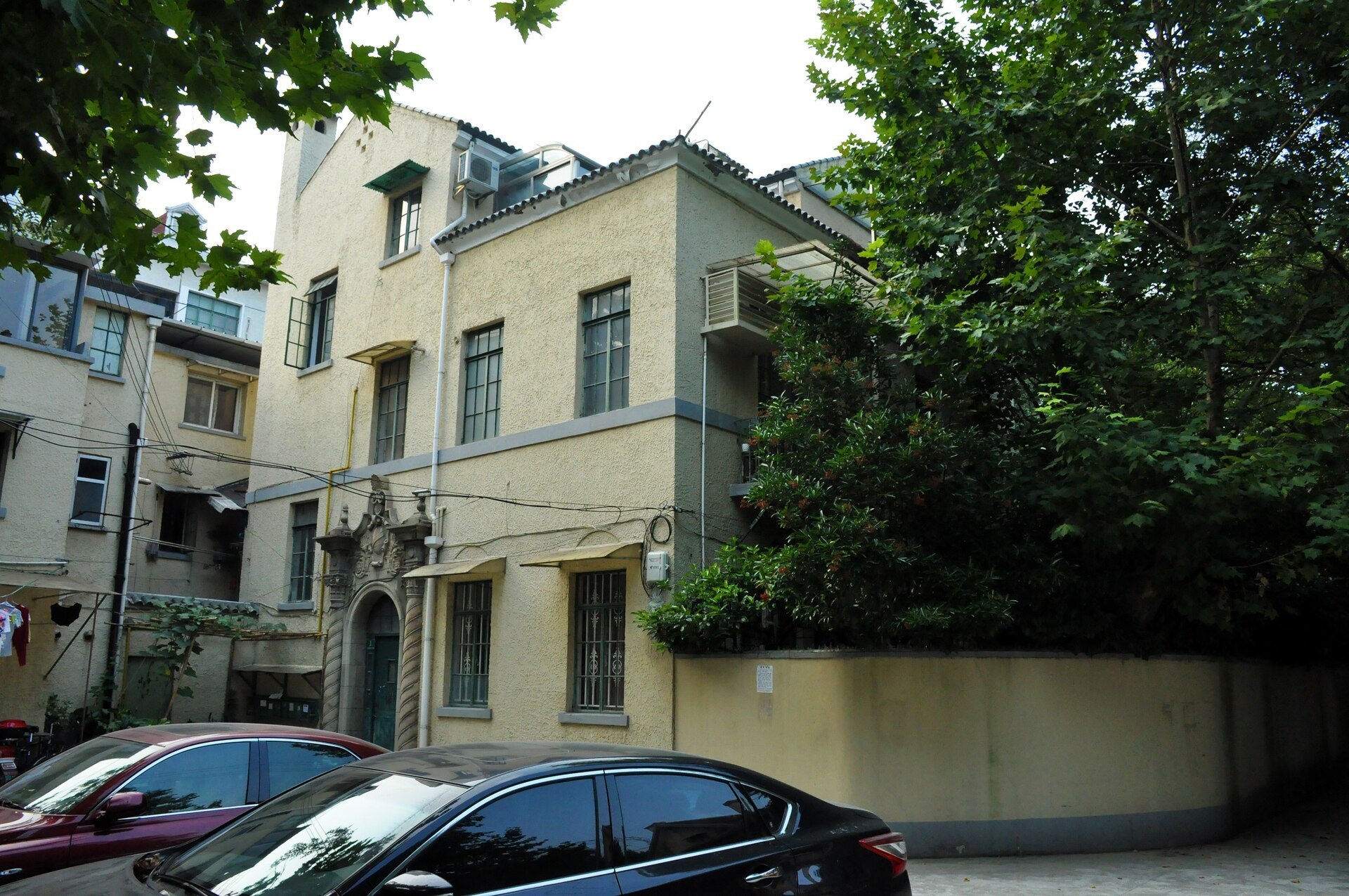 A concession-era villa set back behind a wall and mature trees