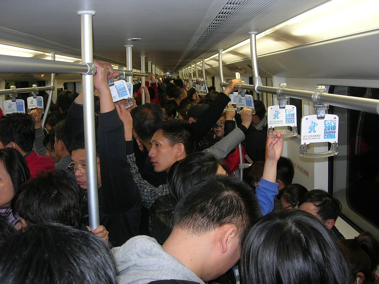 A crowded Shanghai metro carriage with passengers standing, most on their phones