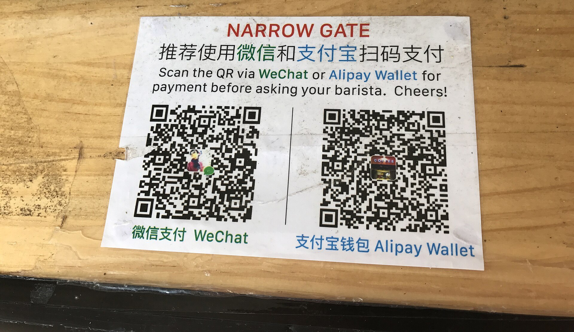 A counter sign showing two QR codes and asking customers to pay by WeChat or Alipay