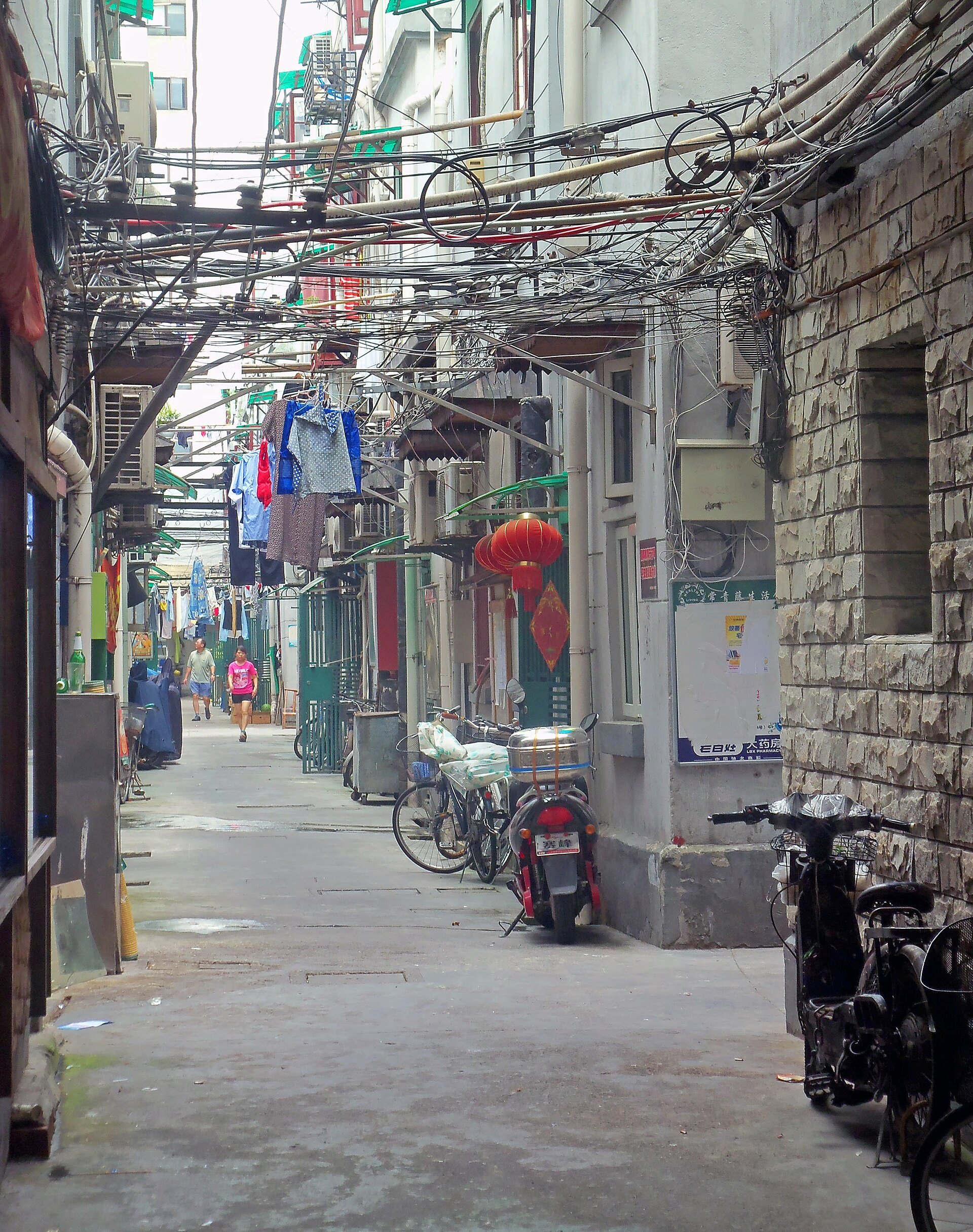 A residential lane with laundry strung overhead and bicycles against the walls