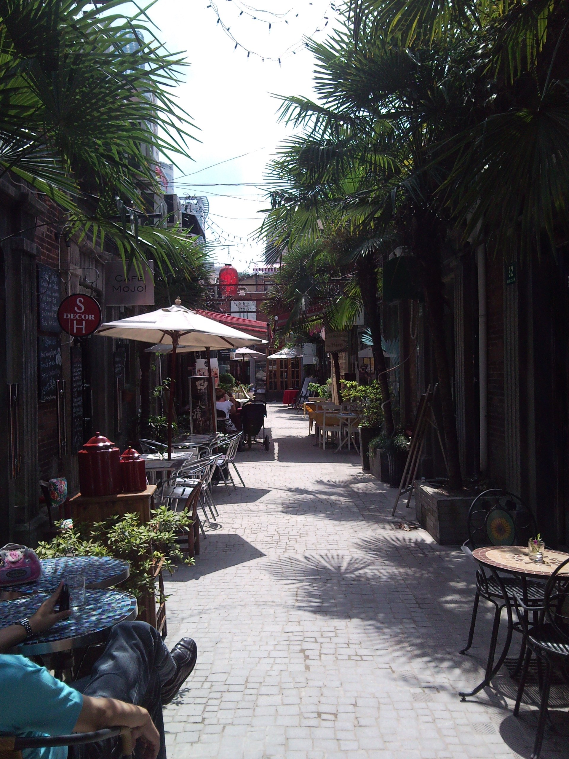 A narrow Tianzifang alley by day, with parasols and shopfronts