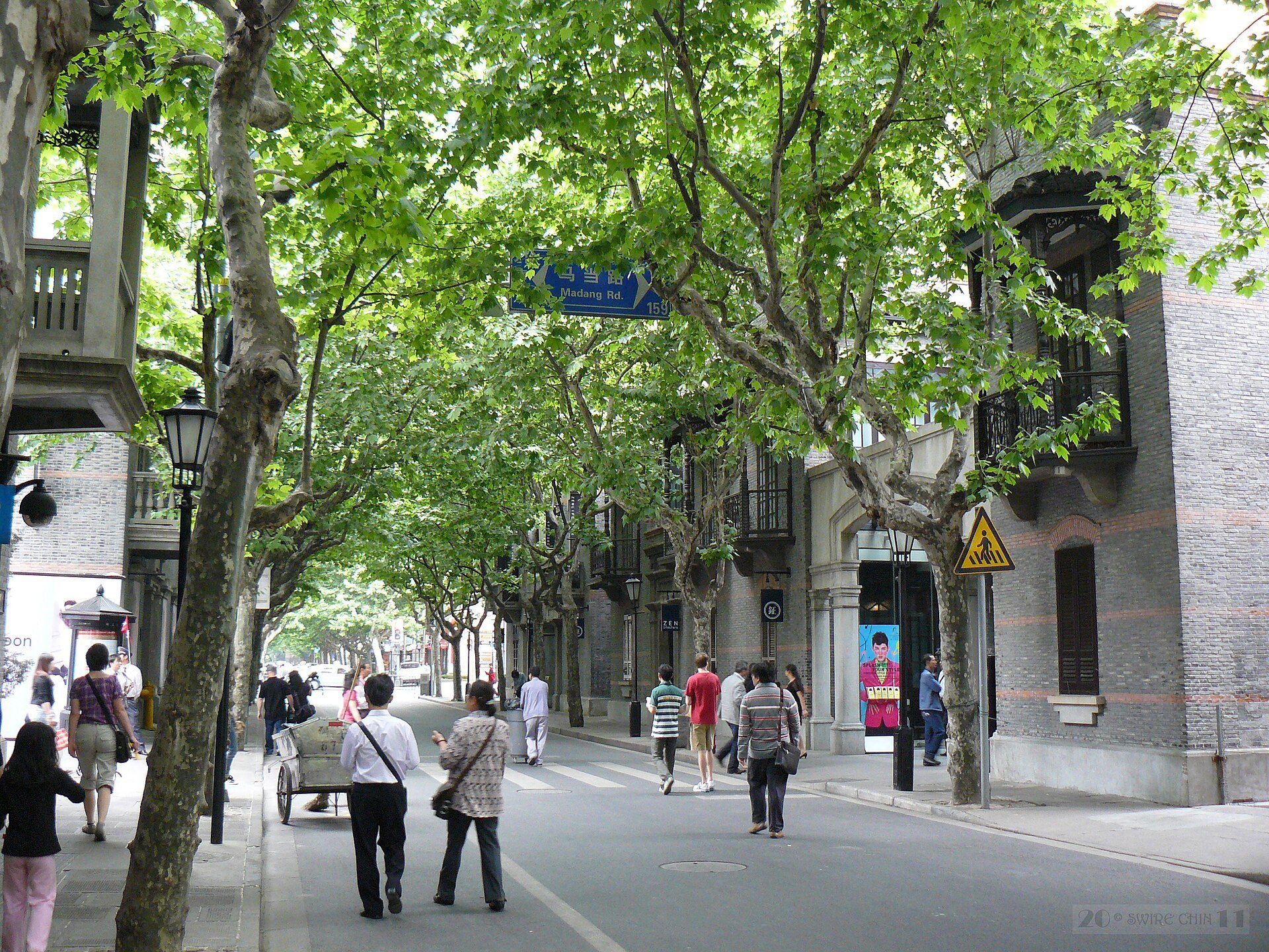 A tree-lined lane through the Xintiandi blocks with people walking